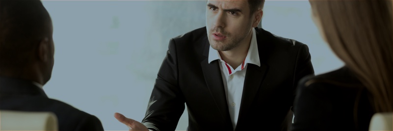 Man in suit addressing two women in an office